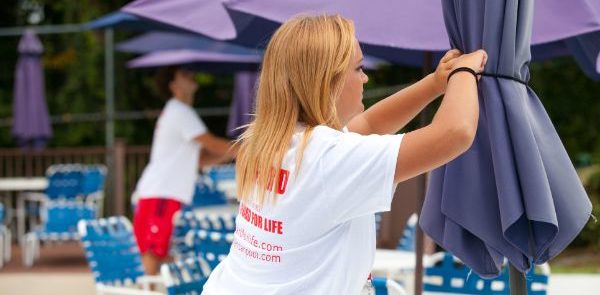 female lifeguard tying up pool umbrella