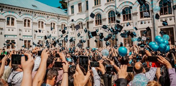 large group of graduates tossing graduation caps in the air
